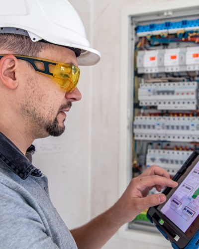 Man, an electrical technician working in a switchboard with fuses. Installation and connection of electrical equipment.
