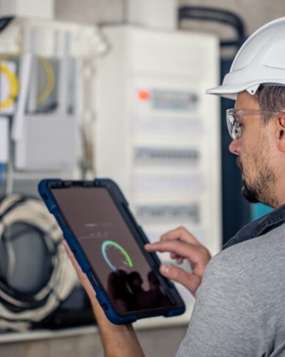 hombre-tecnico-electrico-que-trabaja-cuadro-distribucion-fusibles-usa-tableta_169016-23788