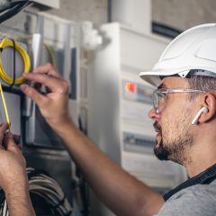 Man, an electrical technician working in a switchboard with fuses. Installation and connection of electrical equipment.